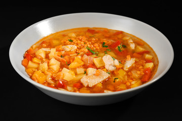 Plate with tasty lentil soup on black background