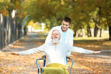 Young caregiver walking with senior man in park