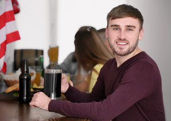 Young man with friends drinking beer in sport bar