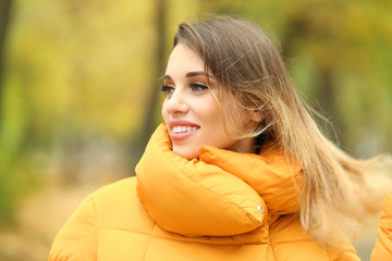 Attractive smiling woman in orange puffer jacket outdoors