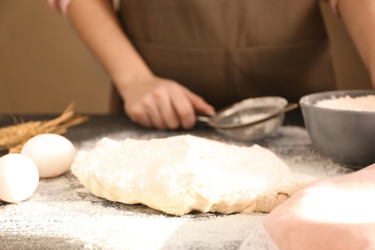 Raw puff pastry and woman at table