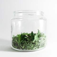 Dry melissa and mint tea in the jar isolated on white background. Homemade and healthy