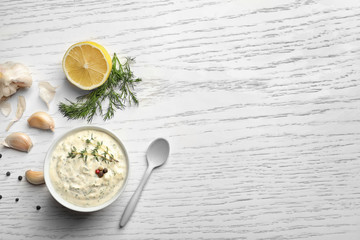 Tasty sauce with garlic in bowl on wooden table
