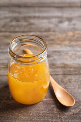 Glass jar with delicious honey and spoon on wooden background