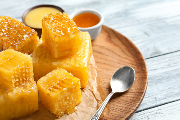 Plate with fresh honeycombs on wooden background, closeup