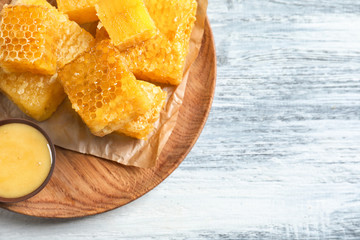 Plate with fresh honeycombs on wooden background, closeup