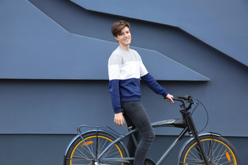 Hipster teenager with bicycle near wall outdoors