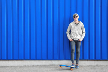Hipster teenager with skateboard near color wall outdoors © Africa Studio