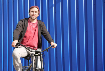 Fototapeta na wymiar Handsome young hipster man with bicycle near wall outdoors