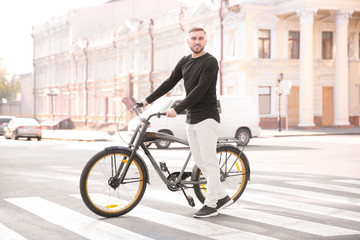Fototapeta na wymiar Handsome young hipster man with bicycle on crosswalk