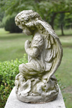 Sad angel marble sculpture. Symbol of eternity, life and death. Antique statue of religion and faith. Vintage image of stone angel in a cemetery.