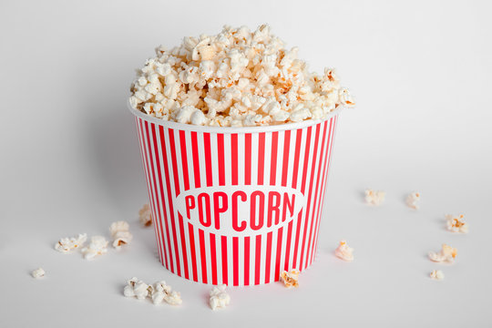 Striped bucket with tasty popcorn on white background