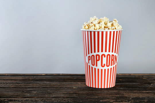Paper cup with tasty popcorn on wooden table