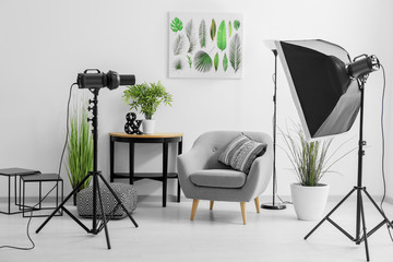 Interior of modern photo studio with armchair and professional equipment