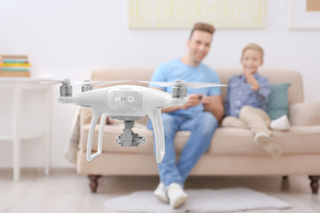 Fototapeta premium Cute boy and his father playing with drone at home
