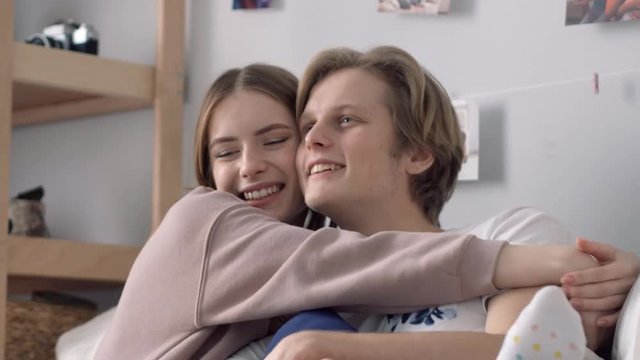 The beginning of relationships. A girl is passionately kissing her boy in his cheeck.