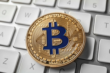 Golden bitcoin on computer keyboard, closeup