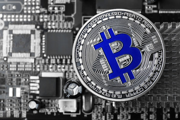 Silver bitcoin on PC motherboard, closeup