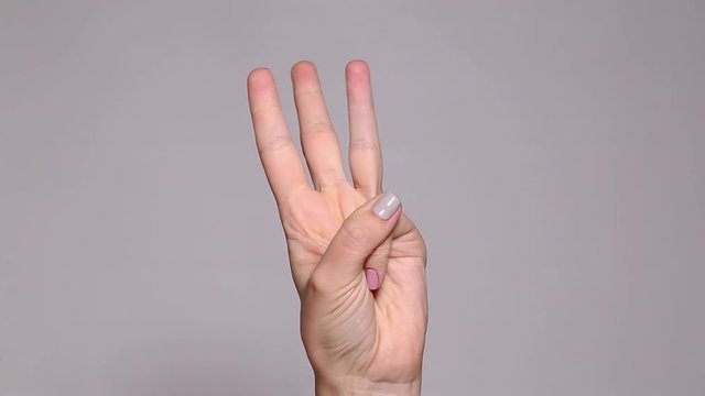 Closeup of isolated female hand counting from 0 to 5. Woman shows fist fist,  then one, two, three, four, five fingers. Manicured nails painted with beautiful modern grey, pink polish. Math concept.