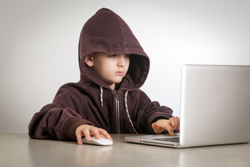 Young hacker in hoodie in front of laptop 