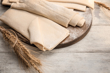 Board with fresh raw puff dough on wooden table