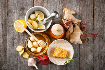 Composition with honey and garlic as natural cold remedies on wooden background, top view