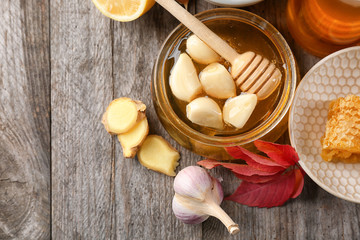 Composition with honey and garlic as natural cold remedies on wooden background, top view