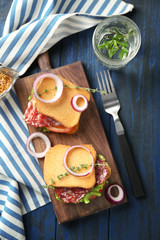 Wooden board with delicious sandwiches on table