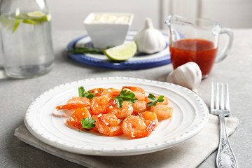 Plate with delicious fried shrimps and chopped garlic on table