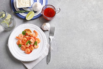 Plate with delicious fried shrimps and chopped garlic on table