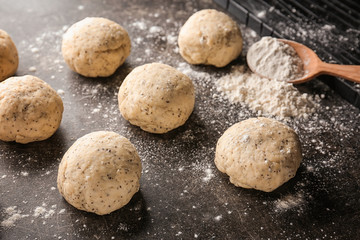 Fototapeta na wymiar Unbaked buns of dough with poppy seeds on table