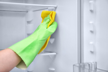 Woman cleaning refrigerator with rag, closeup