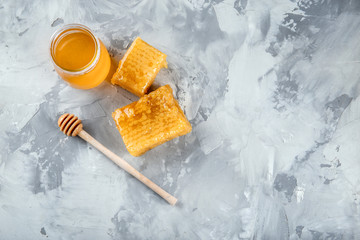 Composition with sweet honey, dipper and honeycombs on grey background