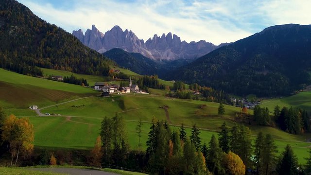 Aerial drone view of Santa Maddalena mountain village in front of the Geisler or Odle Dolomites Group hills, Val di Funes, Trentino Alto Adige. Italy, Europe.
