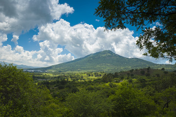 Fototapeta premium Summer landscape with mountains, cloudy sky, green grass and trees in Guatemala.