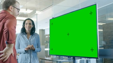 Late at Night Male and Female in Conference Room Have Discussion about Mock-up Chroma Key Green Screen TV.  Shot on RED EPIC-W 8K Helium Cinema Camera.