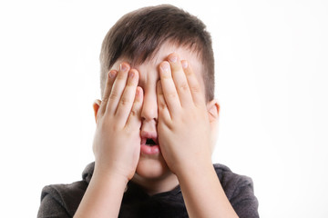 Studio portrait of young boy covering his eyes - see no evil concept