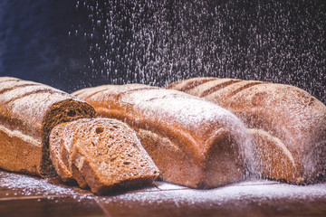 White flour is poured onto a loaf of rye bread.