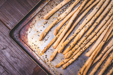 Bread sticks lie on a burnt baking sheet.