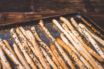Bread sticks and a baking tray are strewn with seeds.