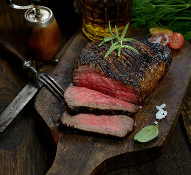 grilled steak with rosemary on a cutting board on a wooden background