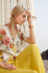 Close-up portrait of a beautiful young woman with a gorgeous bindi on her forehead. Long blonde hair is tangled. She is dressed in a pretty shirt with floral print and yellow skirt