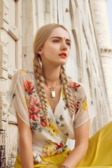 Close-up portrait of a beautiful young woman with a gorgeous bindi on her forehead. Long blonde hair is tangled. She is dressed in a pretty shirt with floral print and yellow skirt