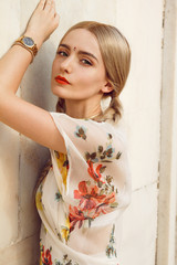 Close-up portrait of a beautiful young woman with gorgeous bindi on her forehead. Long blonde hair is tangled in wonderful hairstyle. And she is dressed in a pretty dress with floral print.