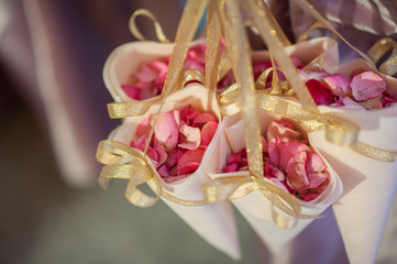 holding rose petals at the wedding. Roses Petals wrapped in paper for decorate in wedding ceremony