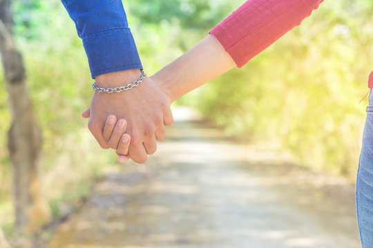 young couple in love holding hand together  walking in a beautiful park with romantic nature background 