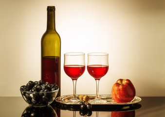 Still life with red wine / A bottle of red wine, two glasses, an apple, and a cup with grapes...