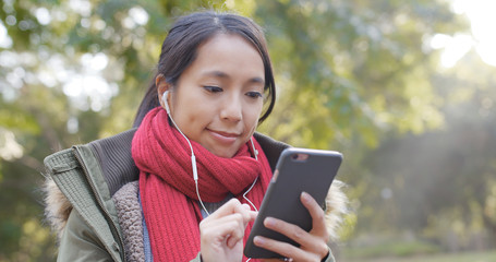 Woman listen to music on cellphone in the Chinese garden