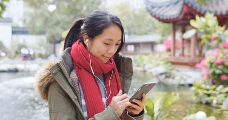 Woman listen to earphone and surf the internet on mobile phone in china