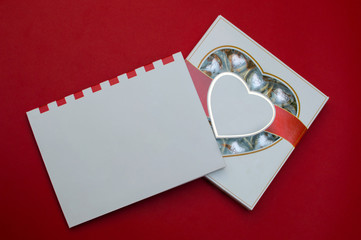 Beautiful mockup for Valentines day. Romantic box of sweets and modern note book on the red background.